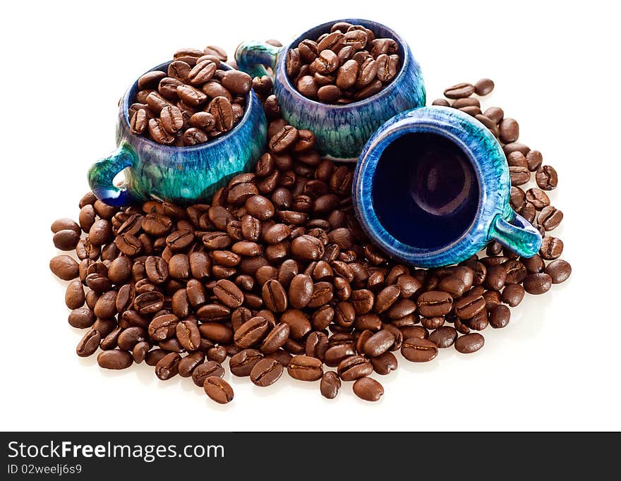 Fresh coffee beans and colorful cups on a white background. Fresh coffee beans and colorful cups on a white background