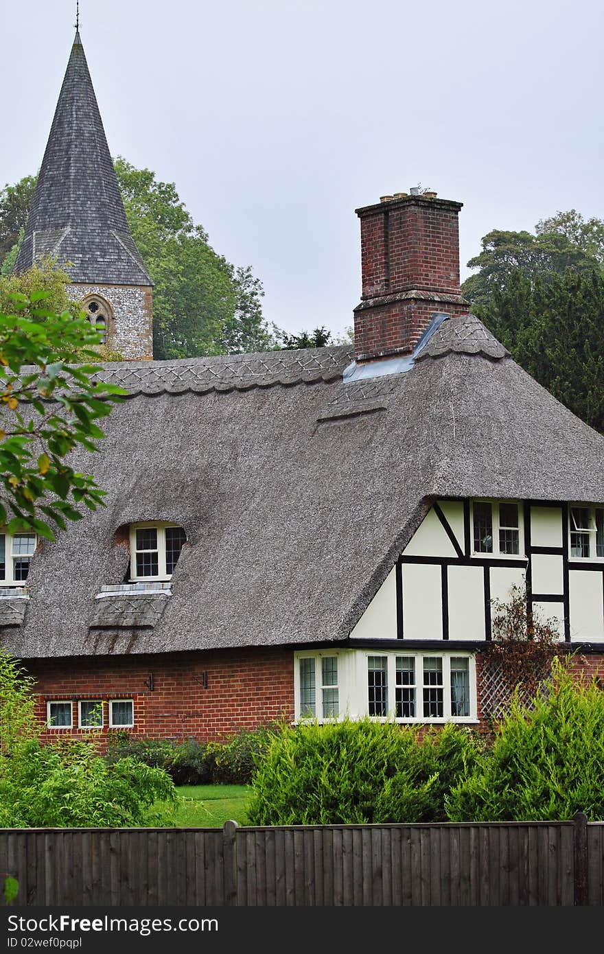 Traditional Thatched English Village Cottage with Church Steeple behind