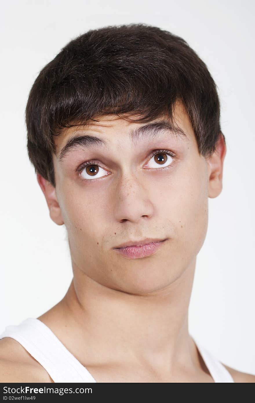 Closeup of a handsome young teenaged guy looking away in thought isolated on white