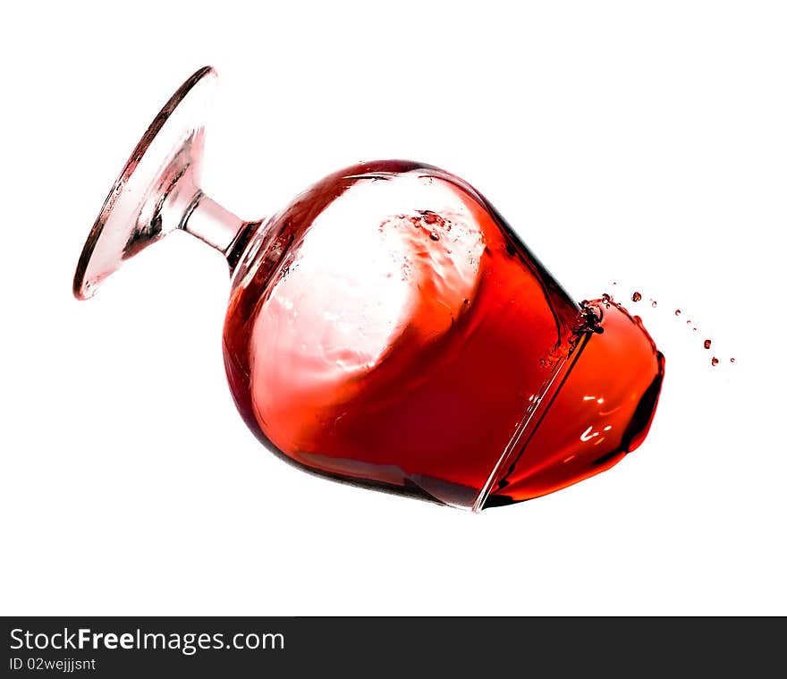 Red wine spilling from a transparent glass isolated on a white background