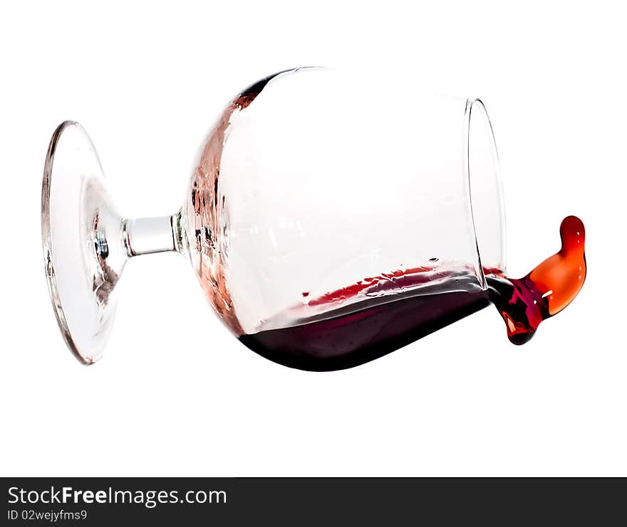 Red wine spilling from a transparent glass isolated on a white background