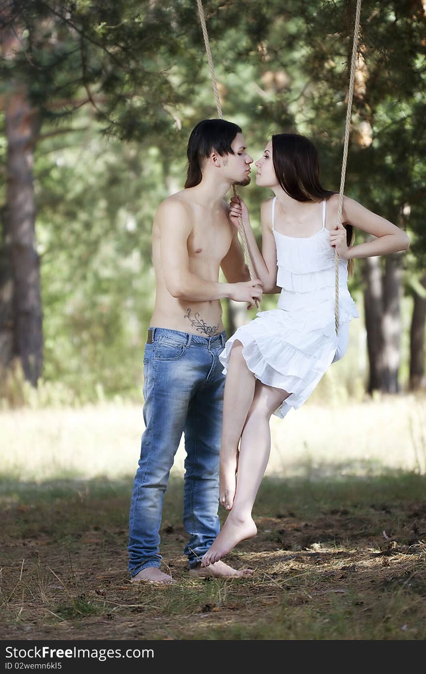 Young happy smiling embracing couple swinging outdoor in nature. Young happy smiling embracing couple swinging outdoor in nature