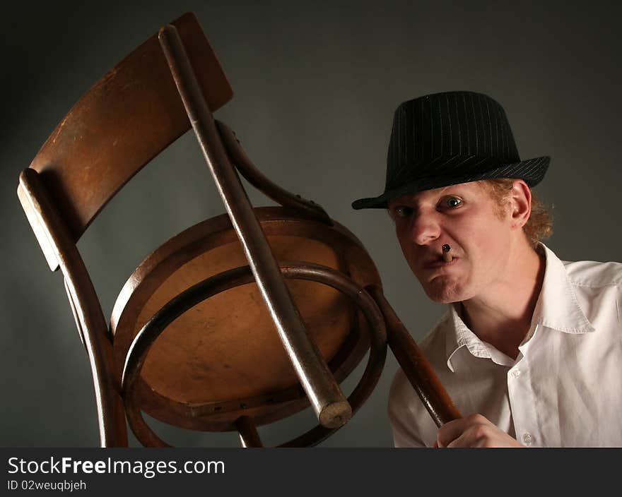 Aggressive guy with chair on dark background. Aggressive guy with chair on dark background