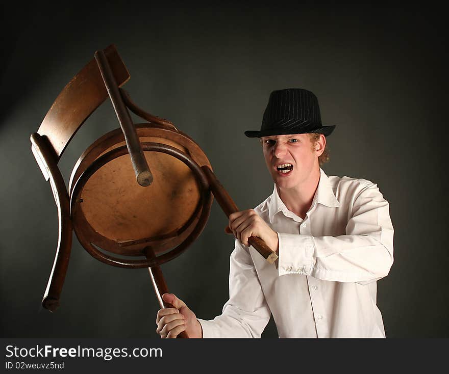 Aggressive guy with chair on dark background. Aggressive guy with chair on dark background