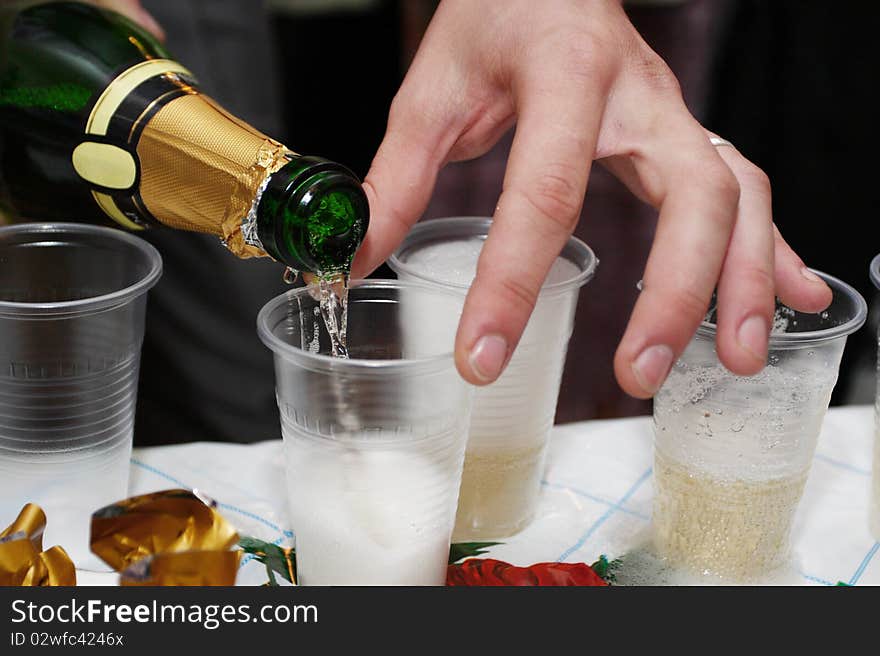 Champagne poured from the boatle to plastic pour. Focus is under the bottle neck