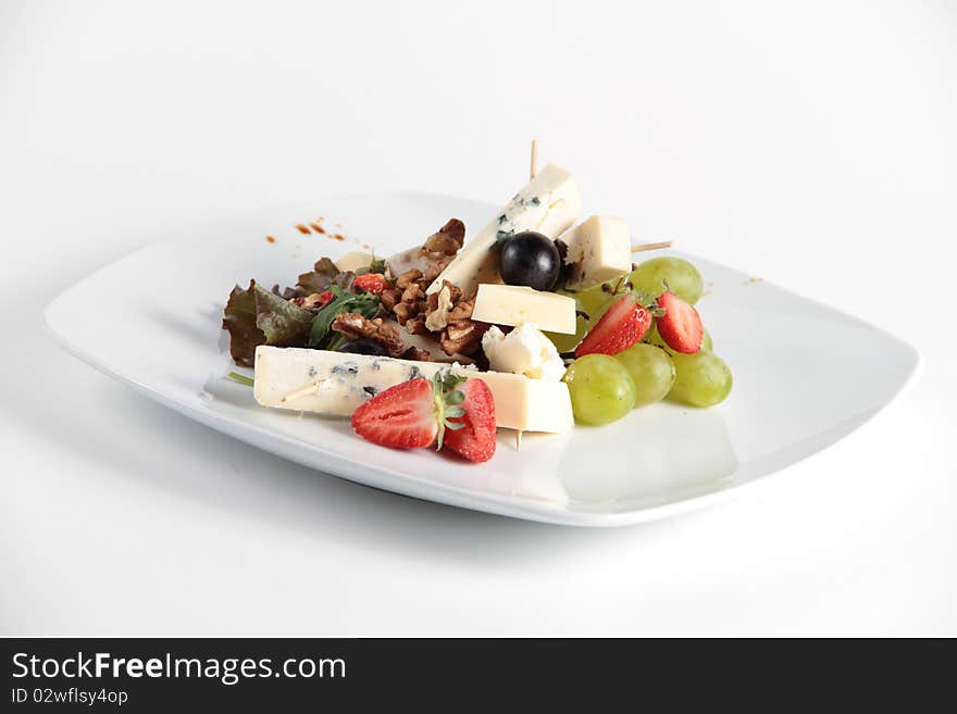 Beautifully decorated cheese and fruit salad served on a white plate. Beautifully decorated cheese and fruit salad served on a white plate