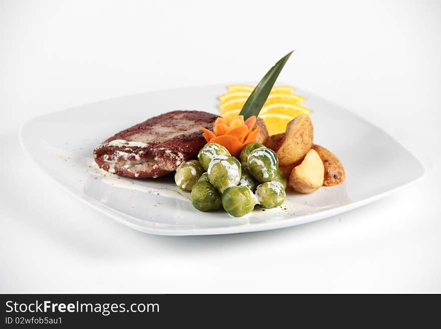 Beaf stake served and decorated with vegetables on a white plate. Beaf stake served and decorated with vegetables on a white plate