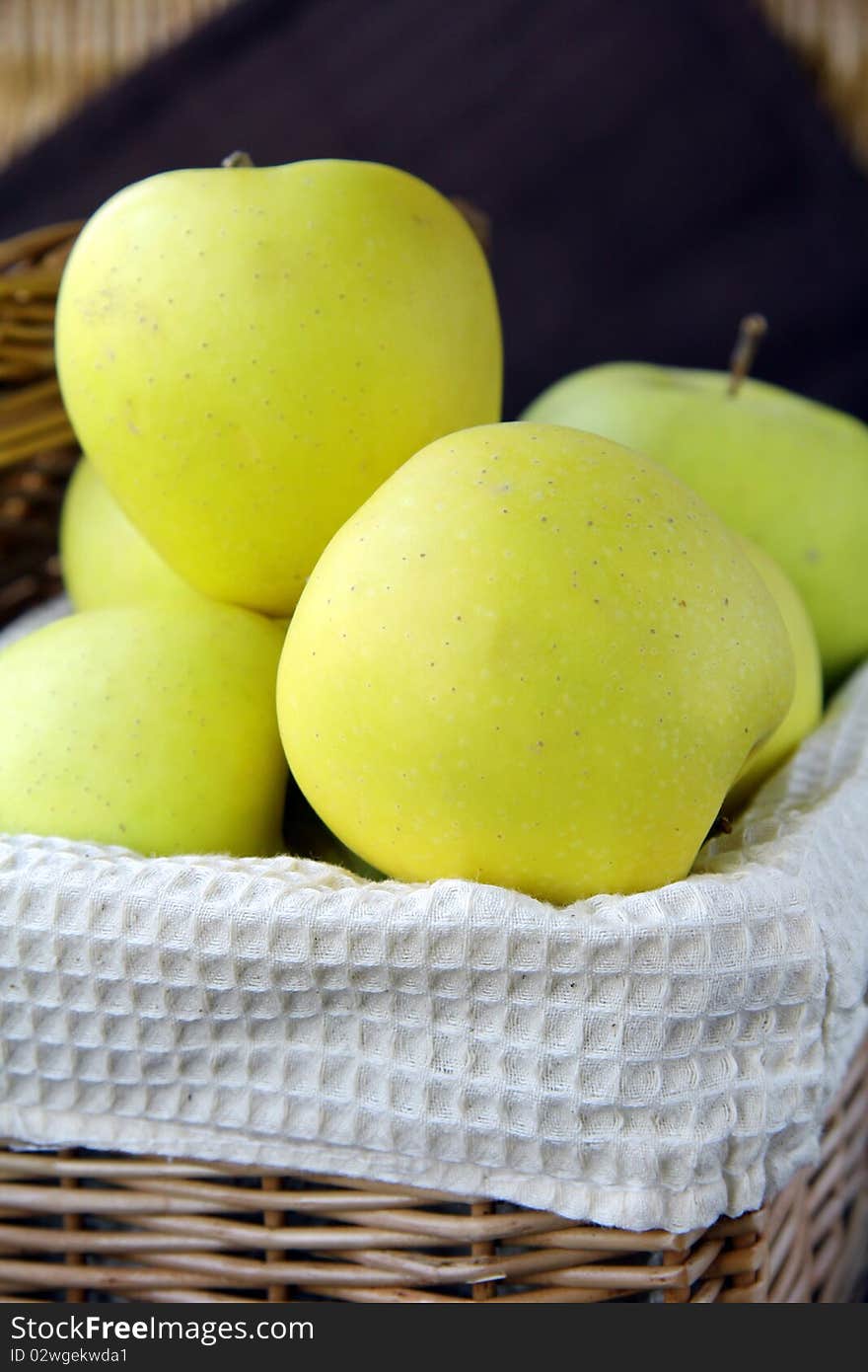 yellow apples in a wicker basket on the table. yellow apples in a wicker basket on the table