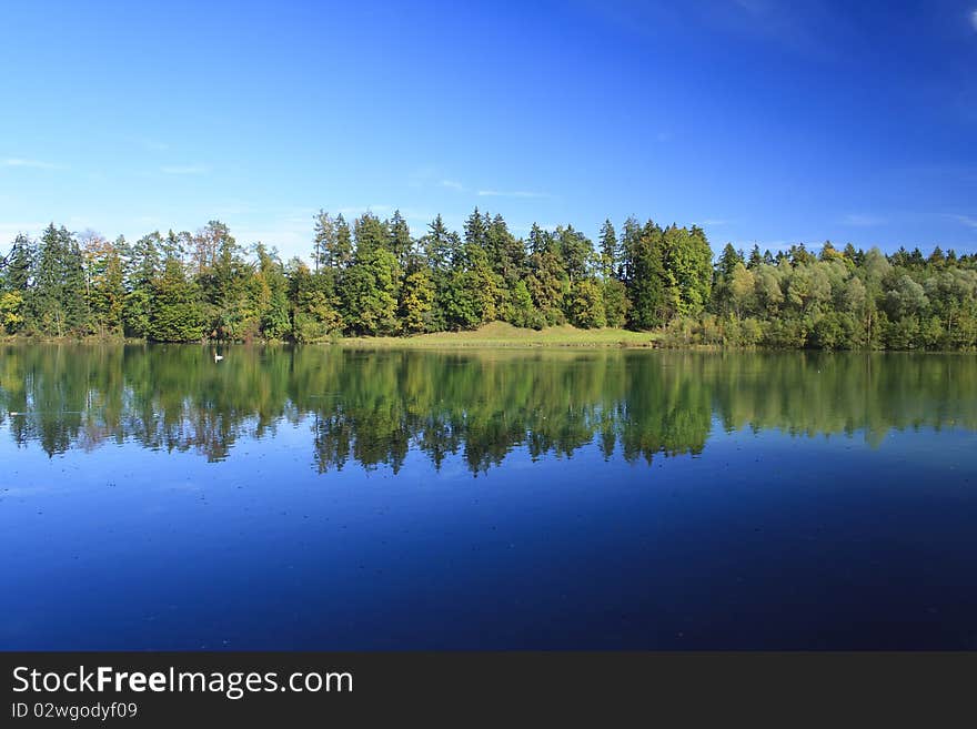 Blue lake with colorful wood and blue sky in autumn. Blue lake with colorful wood and blue sky in autumn