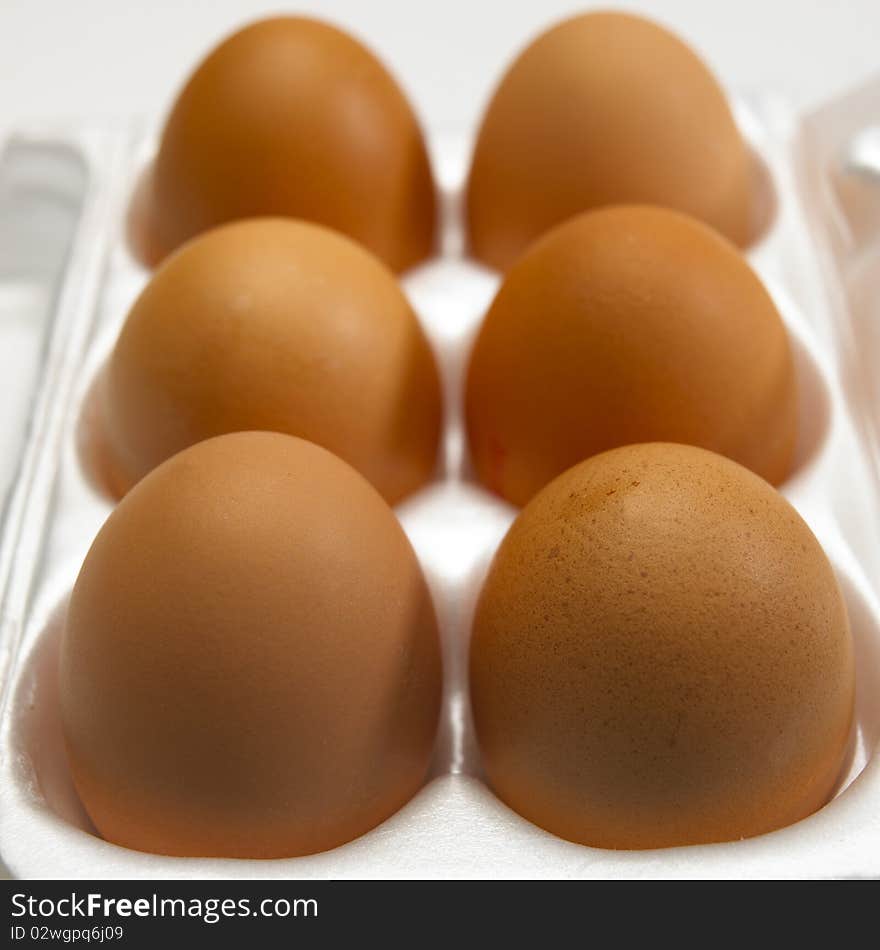 Six brown eggs in white egg box