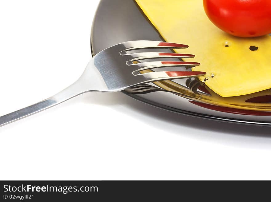 Red tomato and cheese on a black high-gloss plate with stainless fork. Red tomato and cheese on a black high-gloss plate with stainless fork