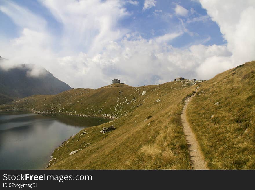 Lake Zancone pastures with mountains and clouds. Lake Zancone pastures with mountains and clouds