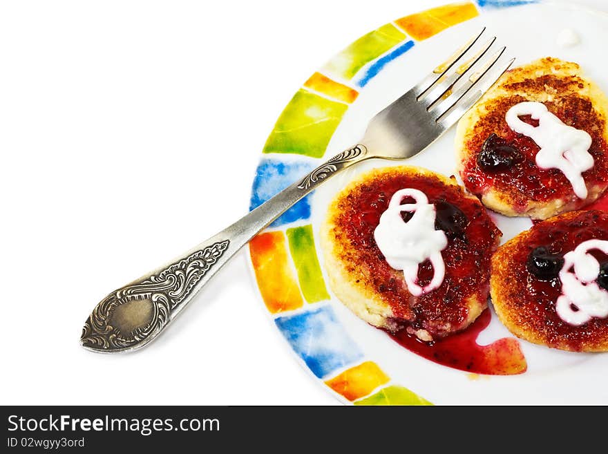 Cottage cheese pancakes with sour cream and blackcurrant jam on a colorful plate with fork. Cottage cheese pancakes with sour cream and blackcurrant jam on a colorful plate with fork