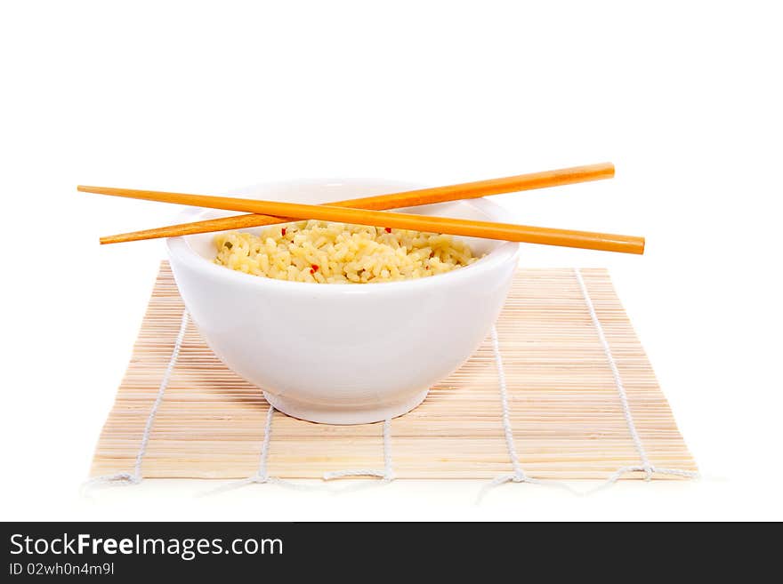 Chopsticks on top of a bowl yellow rice on bamboo mate isolated on white background. Chopsticks on top of a bowl yellow rice on bamboo mate isolated on white background