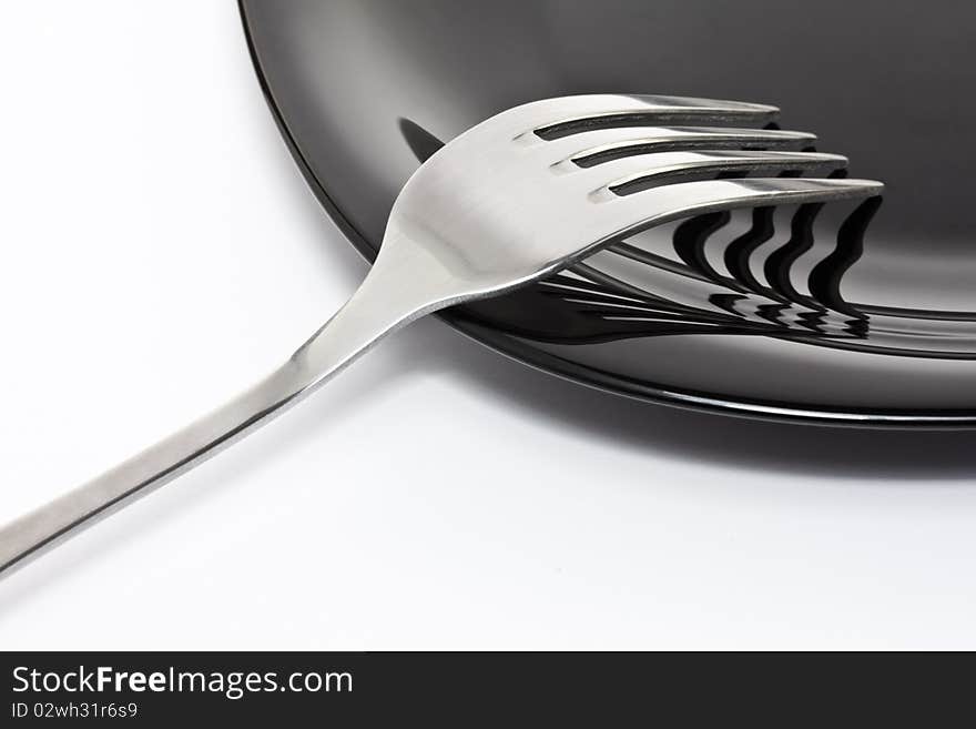 Black high-gloss plate with stainless fork. Black high-gloss plate with stainless fork