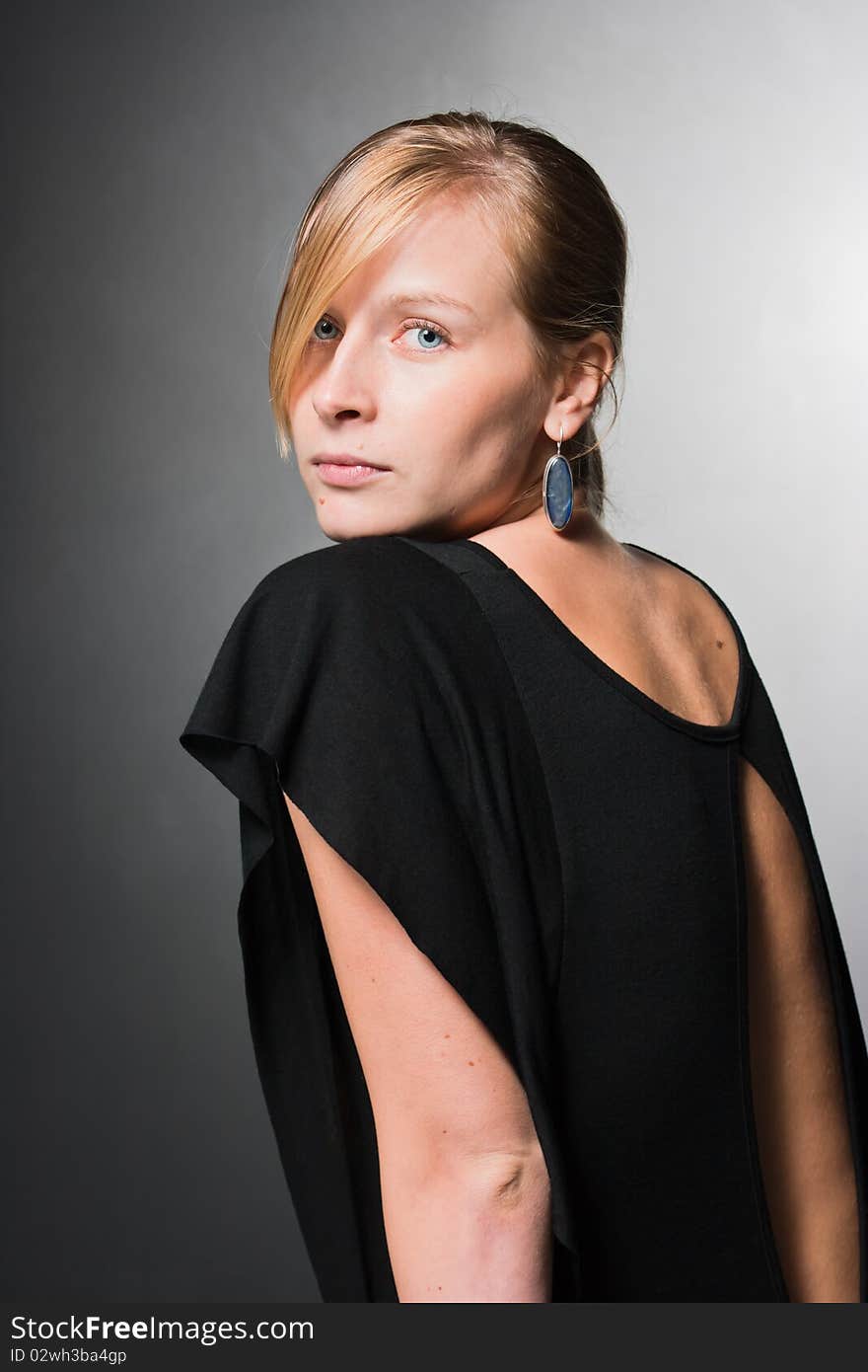 Young woman looking behind. On dark background. Young woman looking behind. On dark background