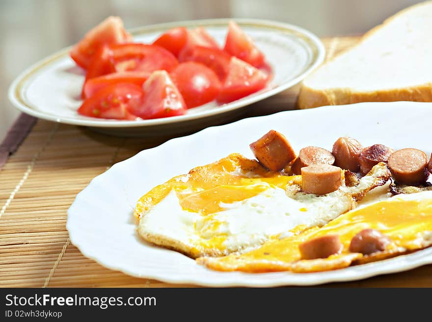 Breakfast with eggs, sausage, bread and tomato