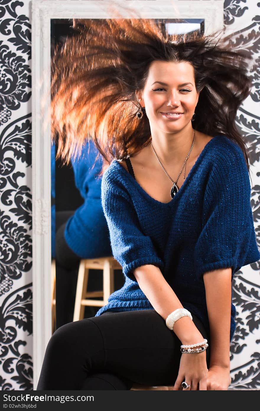 Portrait of attractive woman with hair is shuffled by the wind on a background of mirror. Portrait of attractive woman with hair is shuffled by the wind on a background of mirror