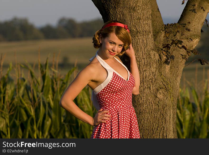 Beautiful pinup girl leaning on a tree in the country side. Beautiful pinup girl leaning on a tree in the country side