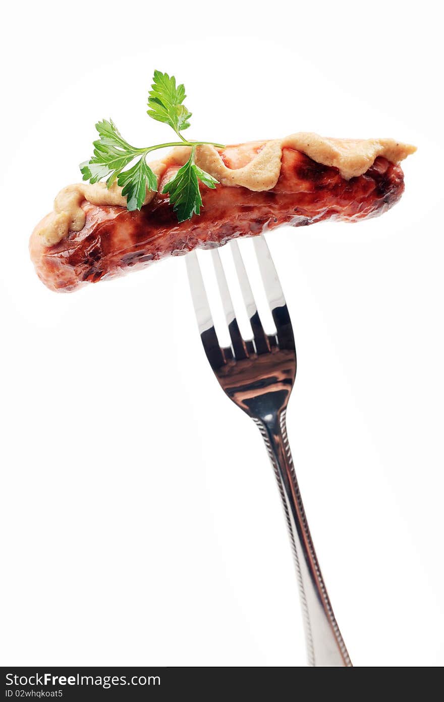 Close-up of fried sausage with mustard on a fork. Isolated over white background. Close-up of fried sausage with mustard on a fork. Isolated over white background.