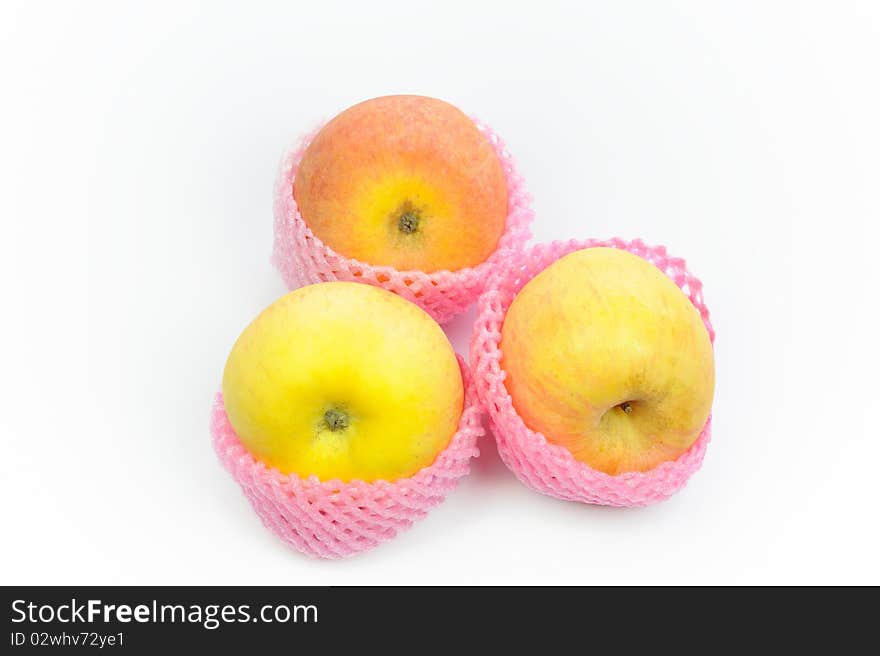 Close up of three apple shipping net on a white surface.