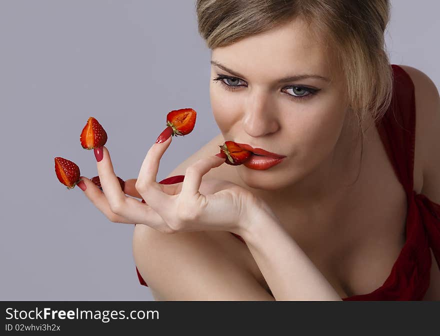 Woman with red strawberries picked on fingertips