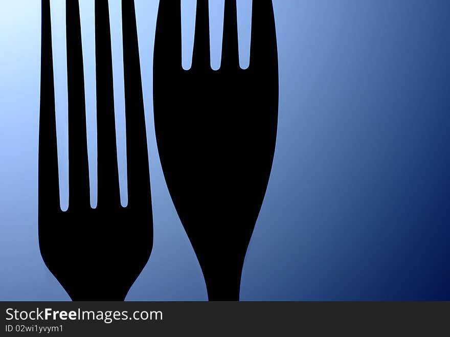 Black silhouette of the two table forks on a blue background