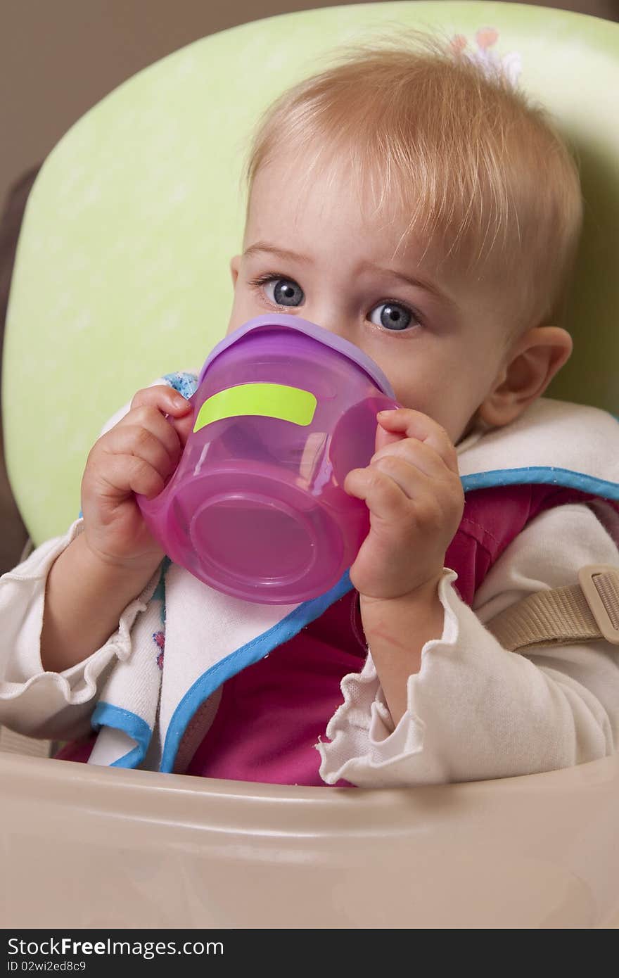 Baby girl drinking from her little sipper cup. Baby girl drinking from her little sipper cup