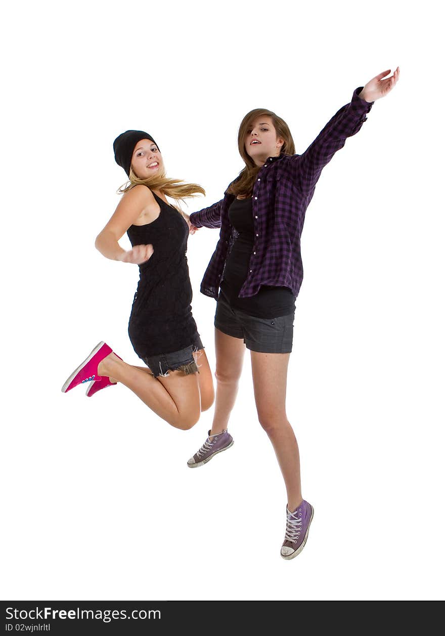 Two young teenage girls with trendy stylish clothes jumpingover white background. Two young teenage girls with trendy stylish clothes jumpingover white background.