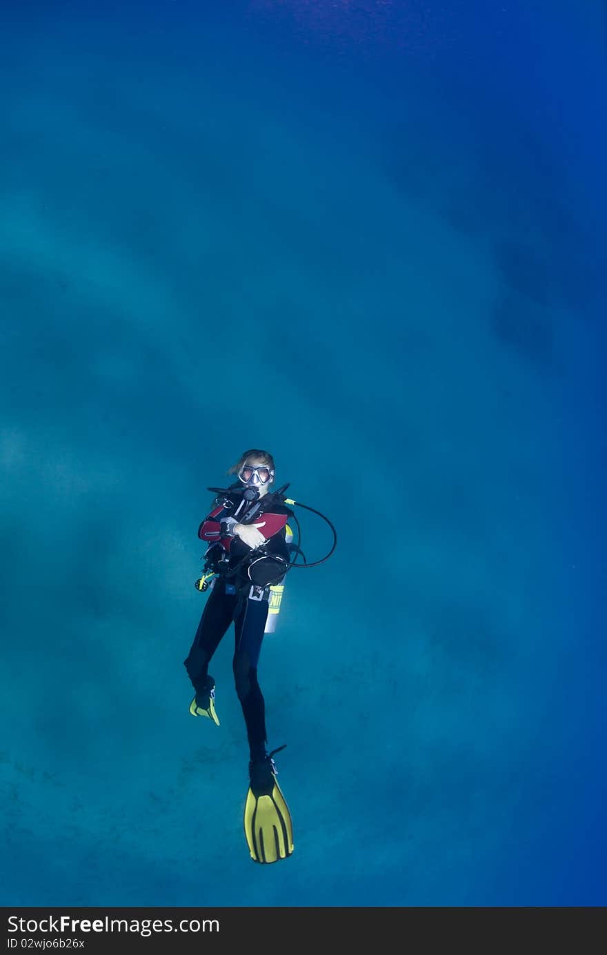 One female scuba diver swimming on her back looking to the surface. One female scuba diver swimming on her back looking to the surface.