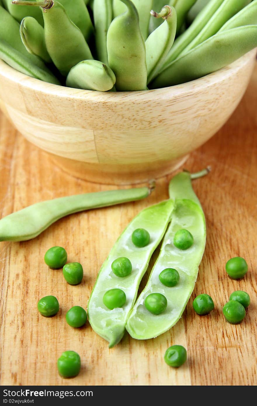 Green peas in a wooden bowl and on the board