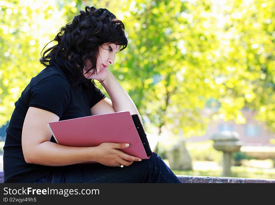 Young student reading on a bench in the park. Young student reading on a bench in the park