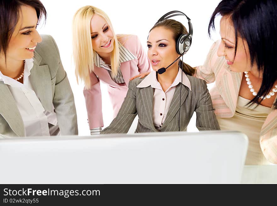 Four beautiful successful businesswomen talking behind laptop, one of them with headset. Four beautiful successful businesswomen talking behind laptop, one of them with headset