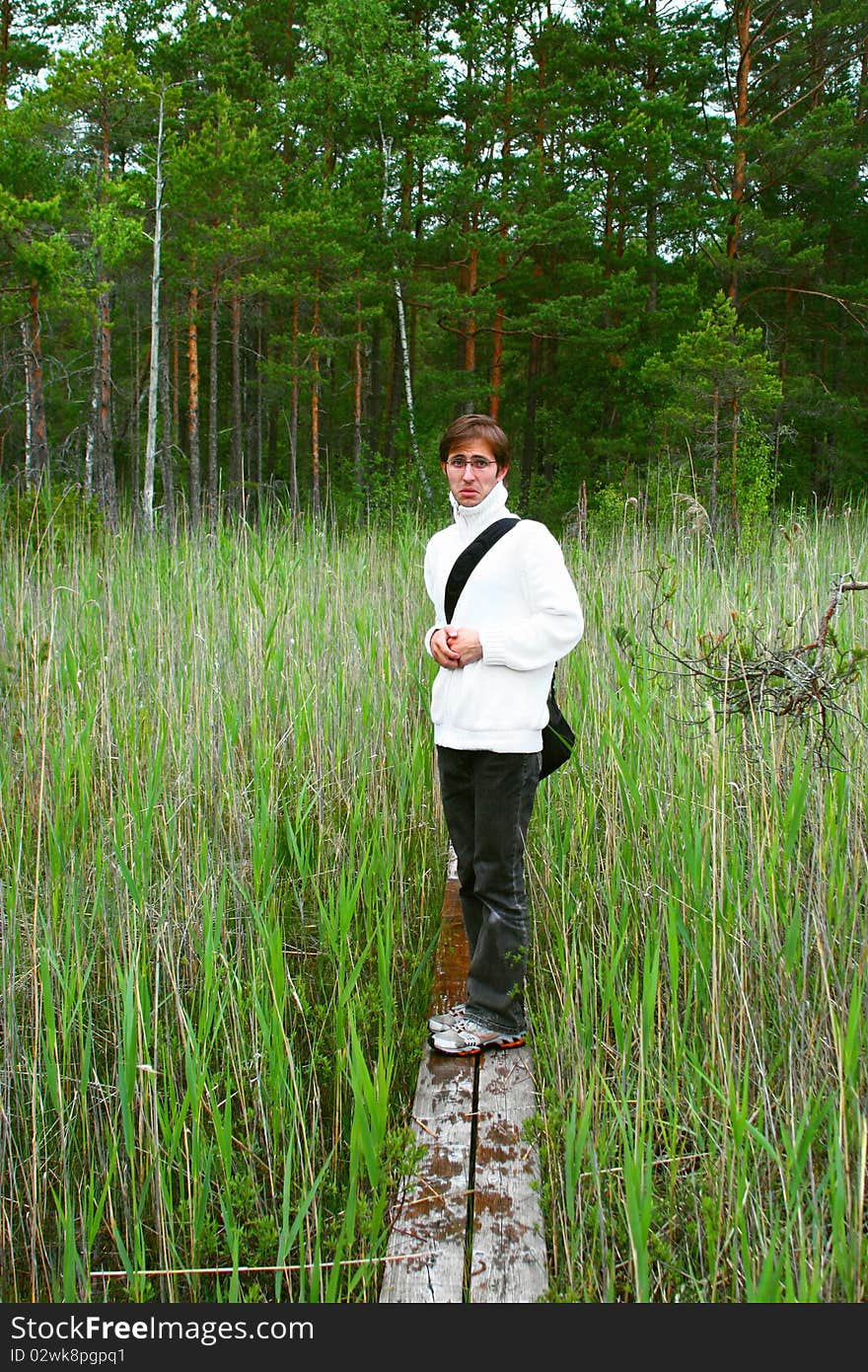 Young scary man is walking through narrow and wet hiking trail on a bog in Engure, Latvia. Young scary man is walking through narrow and wet hiking trail on a bog in Engure, Latvia