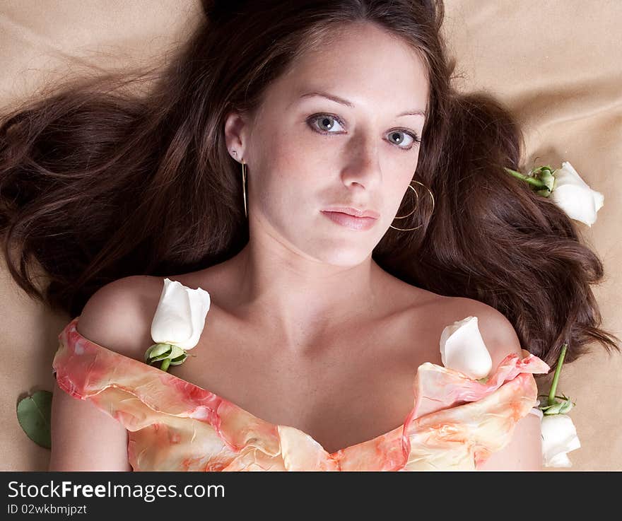 A beautiful portrait of a lovely woman lying on a bed, surrounded by white roses. A beautiful portrait of a lovely woman lying on a bed, surrounded by white roses