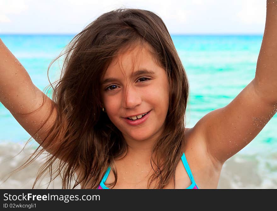 Beautiful girl raising her arms at a beach