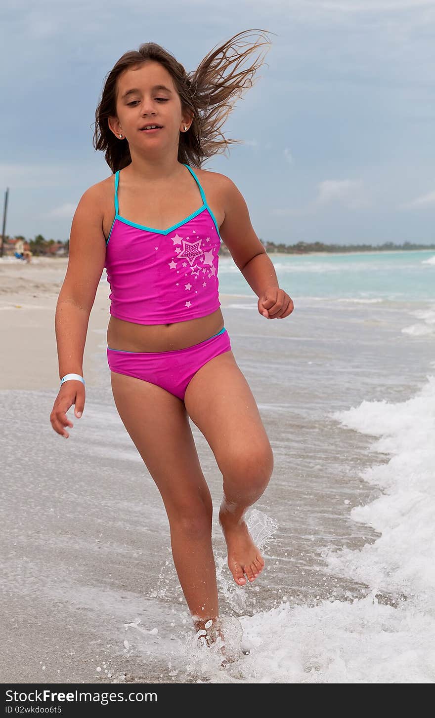 Girl on a pink swimsuit running on a beach