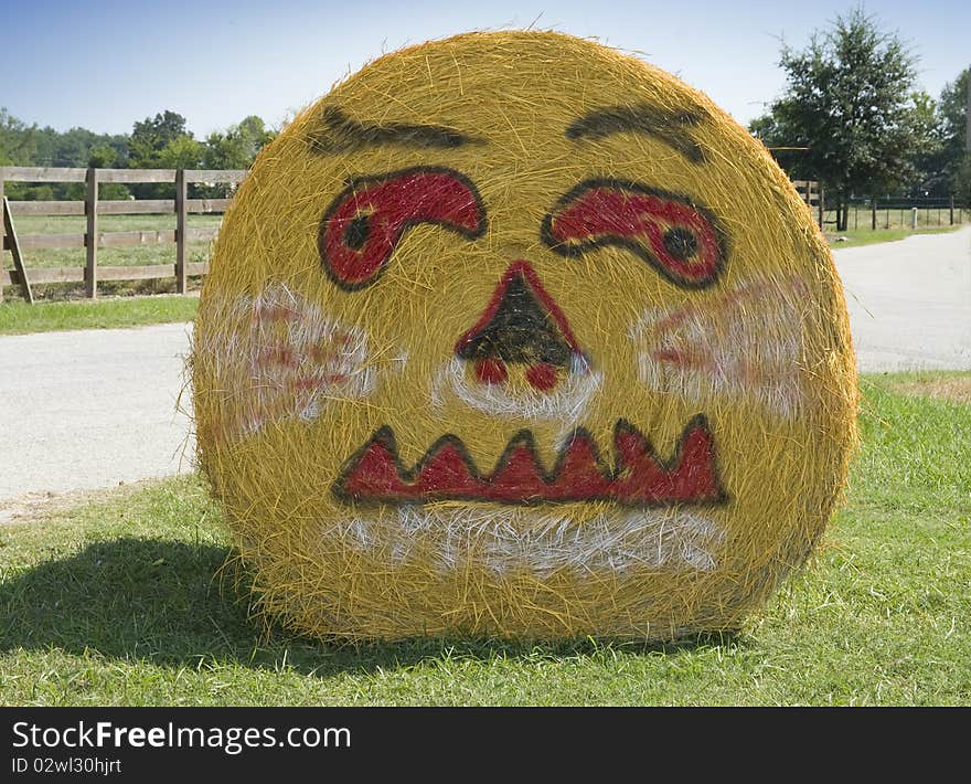 Picture of a pumpkin face painted on side of bale of hale. Picture of a pumpkin face painted on side of bale of hale