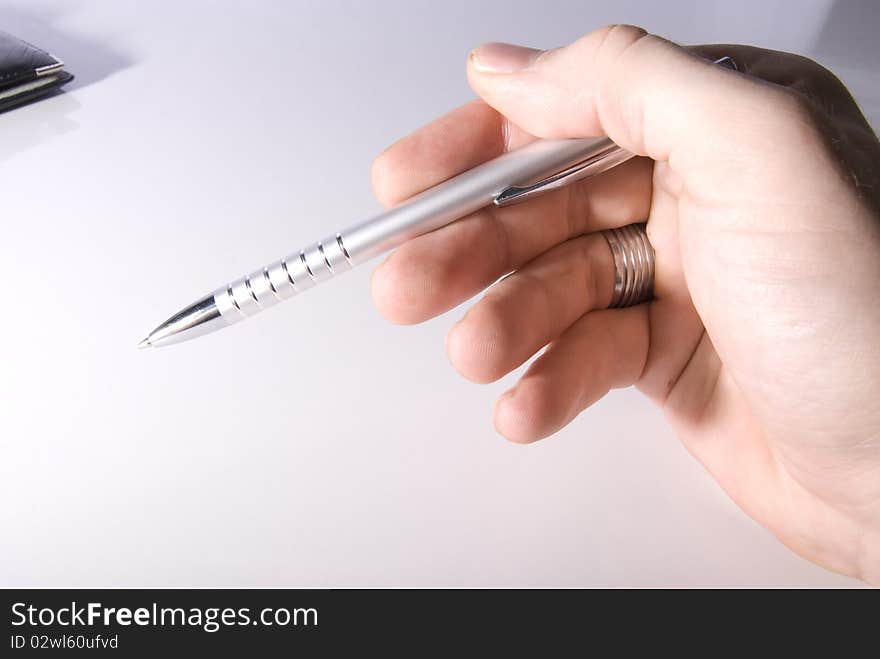 A hand holding a silver pen. A hand holding a silver pen