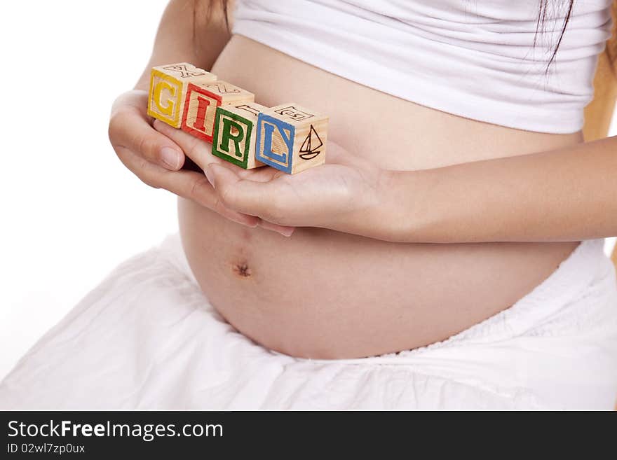 A pregnant woman is holding some blocks against her stomach that spell girl. A pregnant woman is holding some blocks against her stomach that spell girl