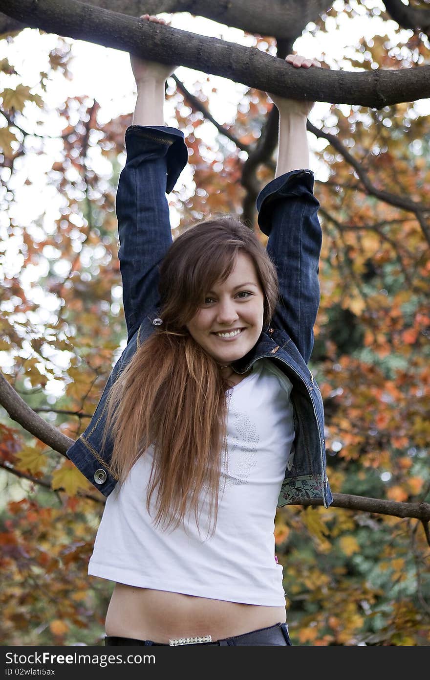 Cheerful girl swinging on a tree in autumn