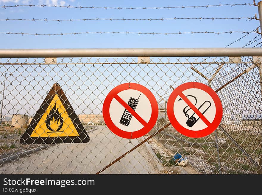 Chainlink and barbed wire fence with warning signs