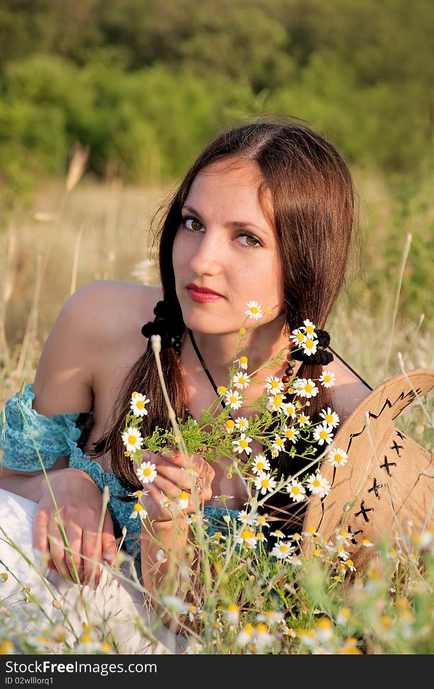 Beautiful woman in a field of flowers chamomile with cowboy hat