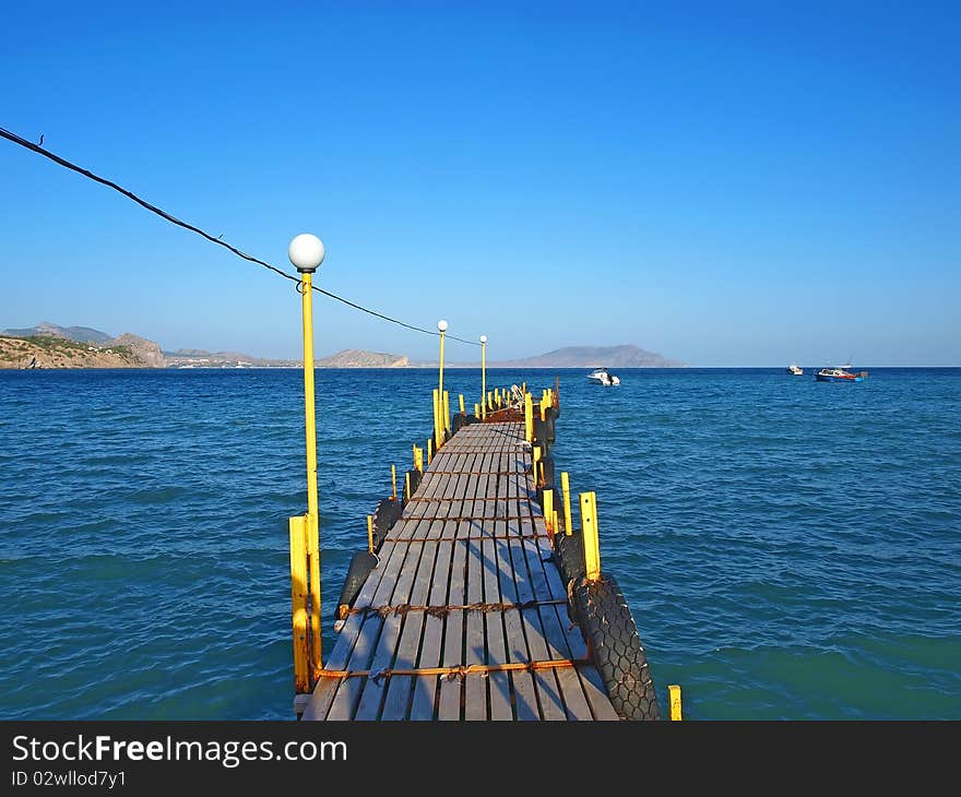 Wooden moorage goes to the sea with ships and mountains. Noviy Svet. Crimea. Ukraine