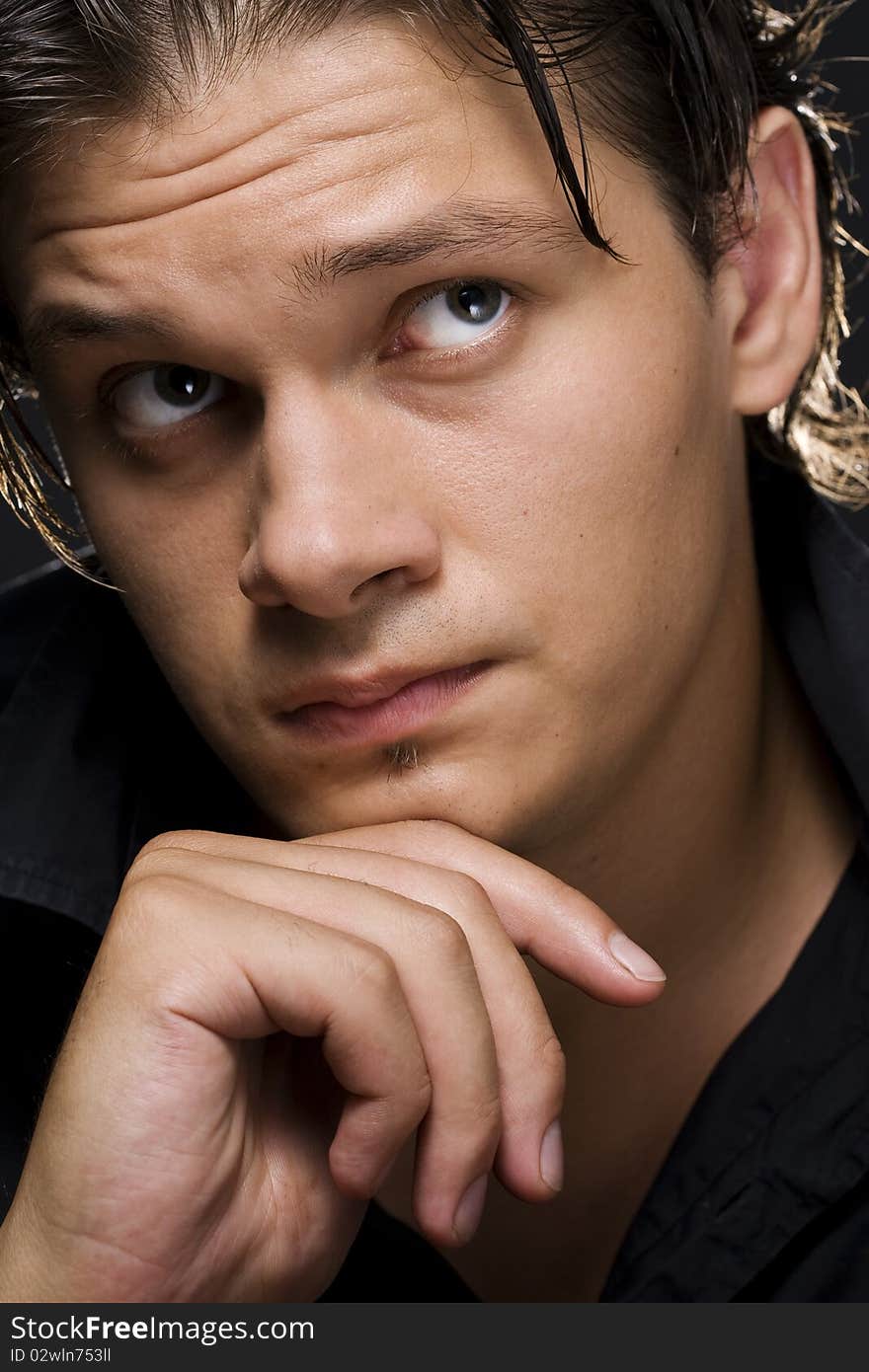 Closeup of a handsome young man thinking against black background