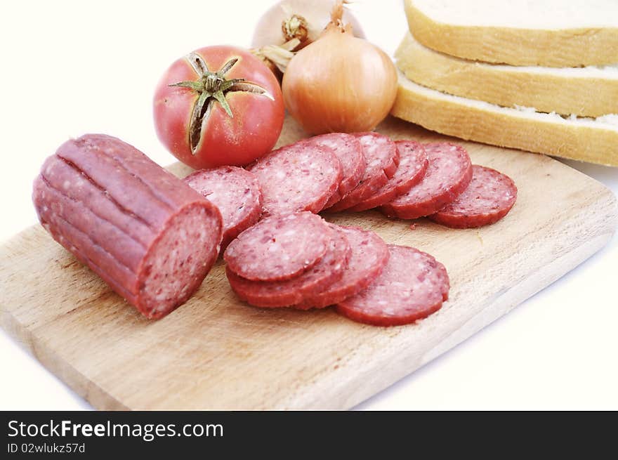 Larded sausage on a chopping board with vegetables. Larded sausage on a chopping board with vegetables