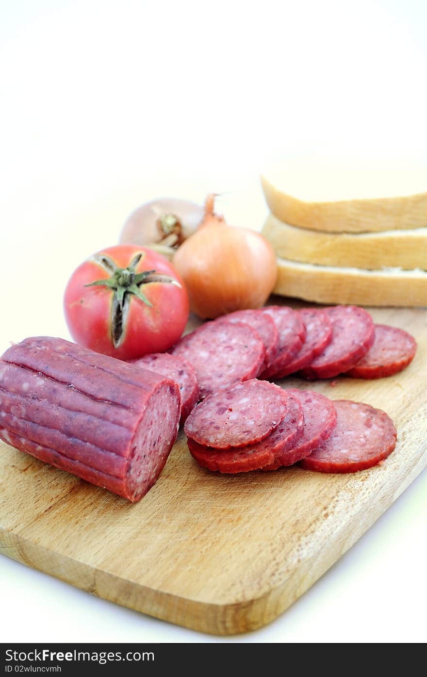 Larded sausage on a chopping board with vegetables. Larded sausage on a chopping board with vegetables