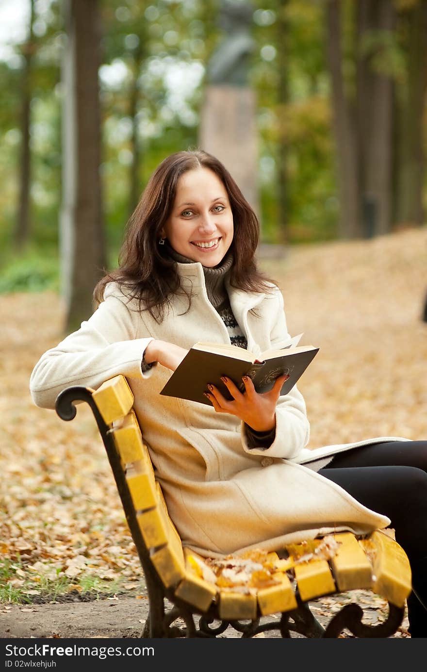 Young Woman Sitting On Bench In Autumn