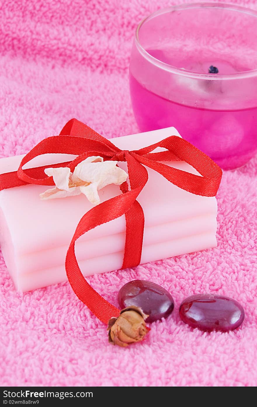 Soap with roses and candle over pink towel