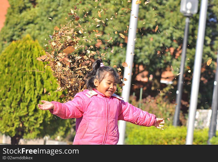 A Malay girl plays with dry leaves during autumn. A Malay girl plays with dry leaves during autumn